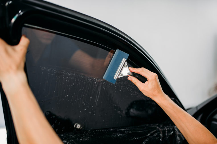 man using squeegee for car tinting film installation